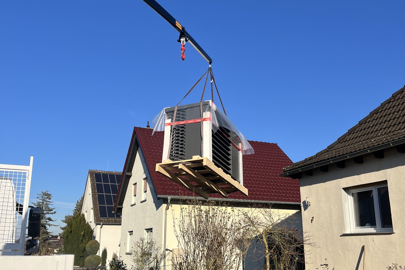 Kranmontage einer Wärmepumpe über ein Wohnhaus durch Weise Haustechnik
